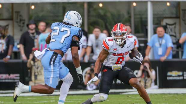 Nov 11, 2023; Orlando, Florida, USA; Oklahoma State Cowboys running back Ollie Gordon II (0) runs the ball in front of UCF Knights linebacker Walter Yates III (27) during the first quarter at FBC Mortgage Stadium