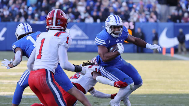 Nov 19, 2022; Provo, Utah, USA; Brigham Young Cougars running back Christopher Brooks (2) jumps through a tackle by Utah Tech Trailblazers defensive back Antonio Mayes (12) in the third quarter at LaVell Edwards Stadium.