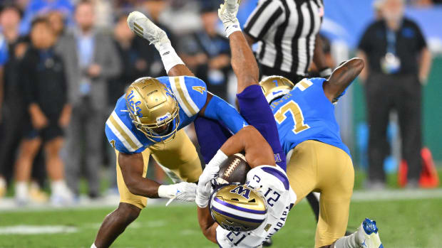 Sep 30, 2022; Pasadena, California, USA; Washington Huskies wide receiver Denzel Boston (12) is stopped by UCLA Bruins defensive back Stephan Blaylock (4) defensive back Mo Osling III (7) after a 15 yard gain and first down in the first quarter at the Rose Bowl.