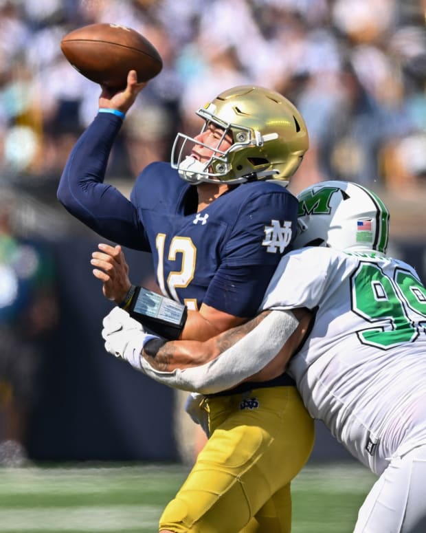 Sep 10, 2022; South Bend, Indiana, USA; Notre Dame Fighting Irish quarterback Tyler Buchner (12) throws as he is hit by Marshall Thundering Herd defensive lineman Isaiah Gibson, Sr. (99) in the first quarter at Notre Dame Stadium.