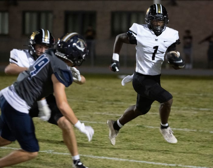 Milton's Raymond Cottrell (No. 1) looks for room to run as the Gulf Breeze defense closes in on September 17, 2022