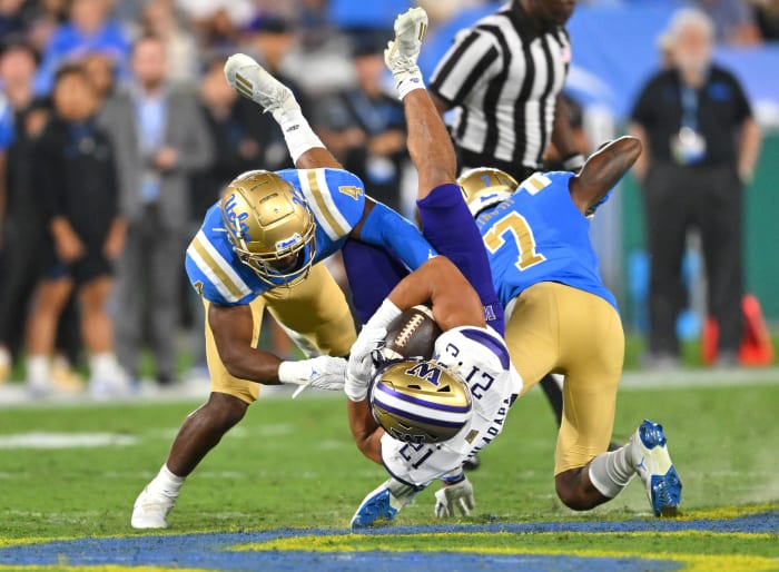 Sep 30, 2022; Pasadena, California, USA; Washington Huskies wide receiver Denzel Boston (12) is stopped by UCLA Bruins defensive back Stephan Blaylock (4) defensive back Mo Osling III (7) after a 15 yard gain and first down in the first quarter at the Rose Bowl.