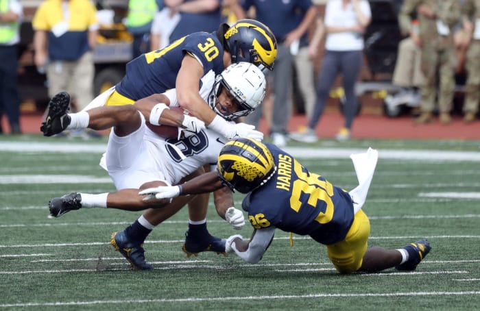 Michigan Wolverines linebacker Jimmy Rolder (30) and defensive back Keshaun Harris (36) tackle Connecticut Huskies wide receiver Dajon Harrison (8) during the second half at Michigan Stadium, Saturday, September 17, 2022.