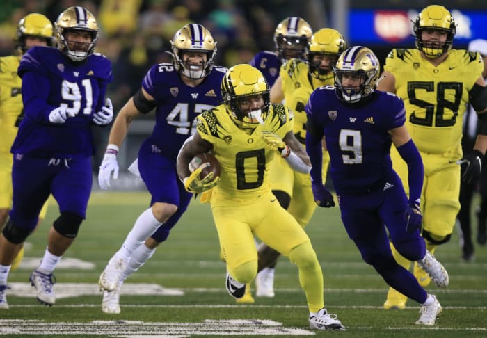 Oregon's Bucky Irving, center, breaks through the Washington defense during the second quarter Saturday, Nov. 12, 2022, at Autzen Stadium in Eugene, Ore