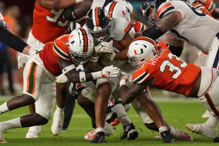Sep 30, 2021; Miami Gardens, Florida, USA; Miami Hurricanes safety Gilbert Frierson (3) and defensive lineman Chantz Williams (33) tackle Virginia Cavaliers tailback Wayne Taulapapa (21) during the first half at Hard Rock Stadium.