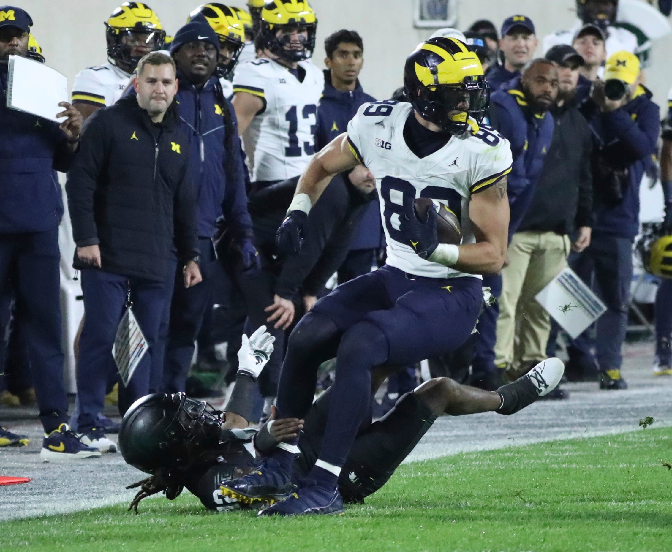 Michigan Wolverines tight end AJ Barner (89) makes a catch against Michigan State Spartans defensive back Chester Kimbrough (12) during second-half action at Spartan Stadium in East Lansing on Saturday, Oct. 21, 2023.