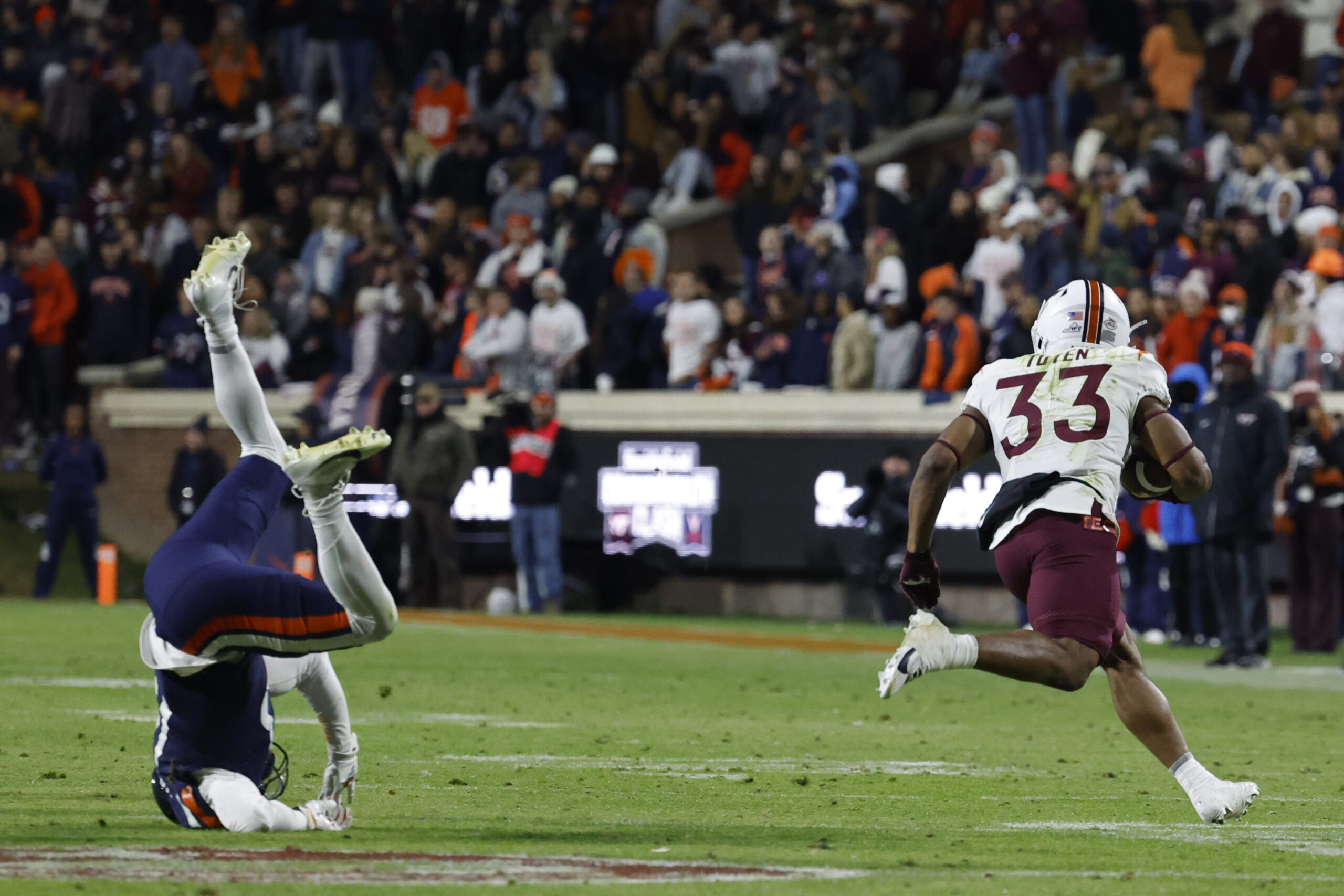 Nov 25, 2023; Charlottesville, Virginia, USA; Virginia Tech Hokies running back Bhayshul Tuten (33) carries the ball past Virginia Cavaliers cornerback Sam Westfall (13) during the third quarter at Scott Stadium.