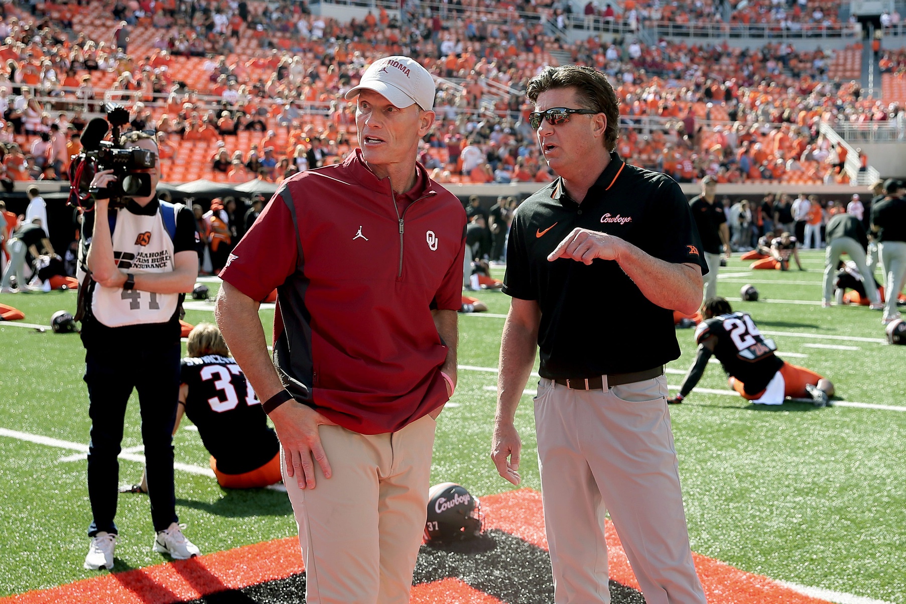 Oklahoma State coach Mike Gundy, right, and Oklahoma coach Brent Venables talk before a Bedlam college football game between the Oklahoma State University Cowboys (OSU) and the University of Oklahoma Sooners (OU) at Boone Pickens Stadium in Stillwater, Okla., Saturday, Nov. 4, 2023.