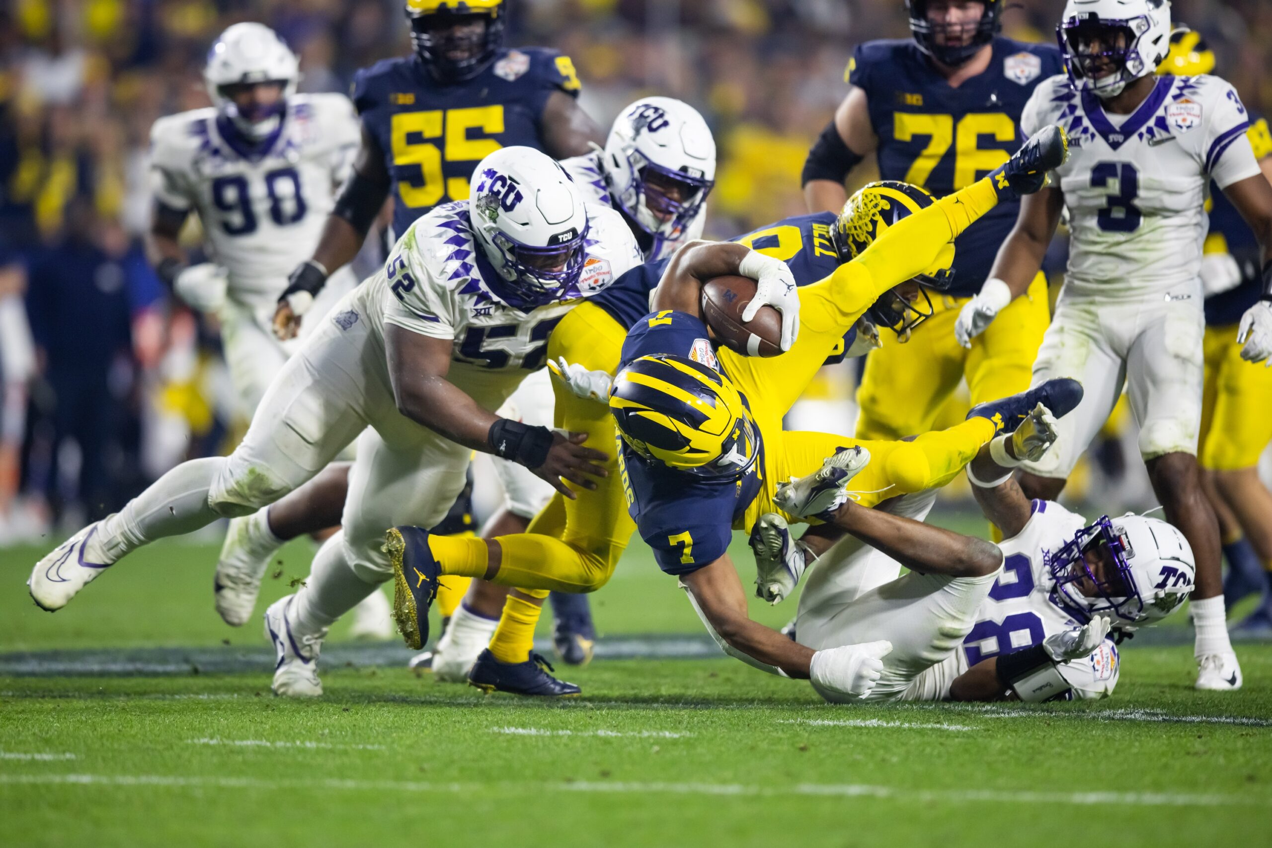Dec 31, 2022; Glendale, Arizona, USA; Michigan Wolverines running back Donovan Edwards (7) is tackled by TCU Horned Frogs defensive lineman Damonic Williams (52) and safety Millard Bradford (28) in the fourth quarter of the 2022 Fiesta Bowl at State Farm Stadium.