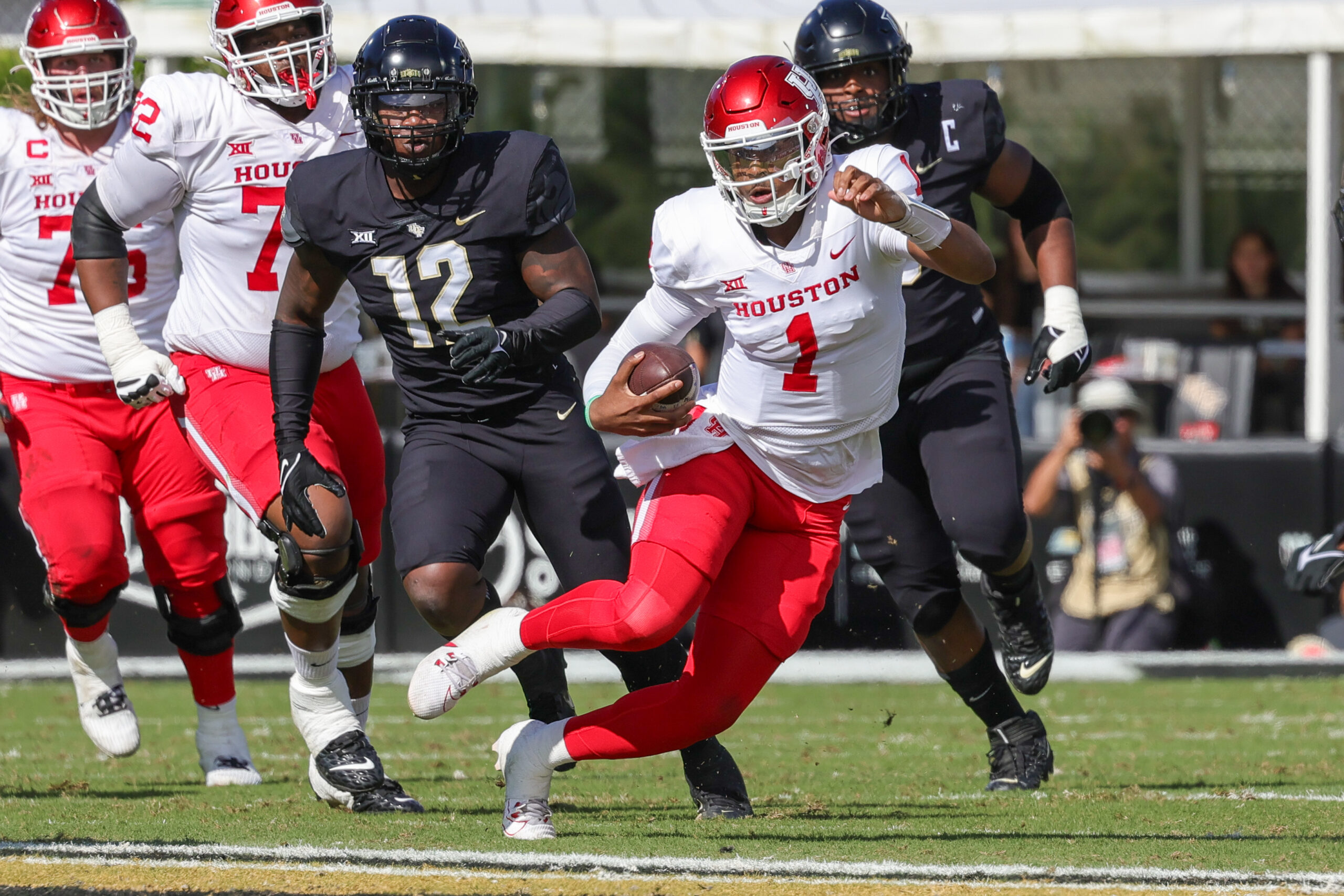 Nov 25, 2023; Orlando, Florida, USA; Houston Cougars quarterback Donovan Smith (1) runs the ball in front of UCF Knights defensive end Shaun Peterson Jr. (12) during the second quarter at FBC Mortgage Stadium.