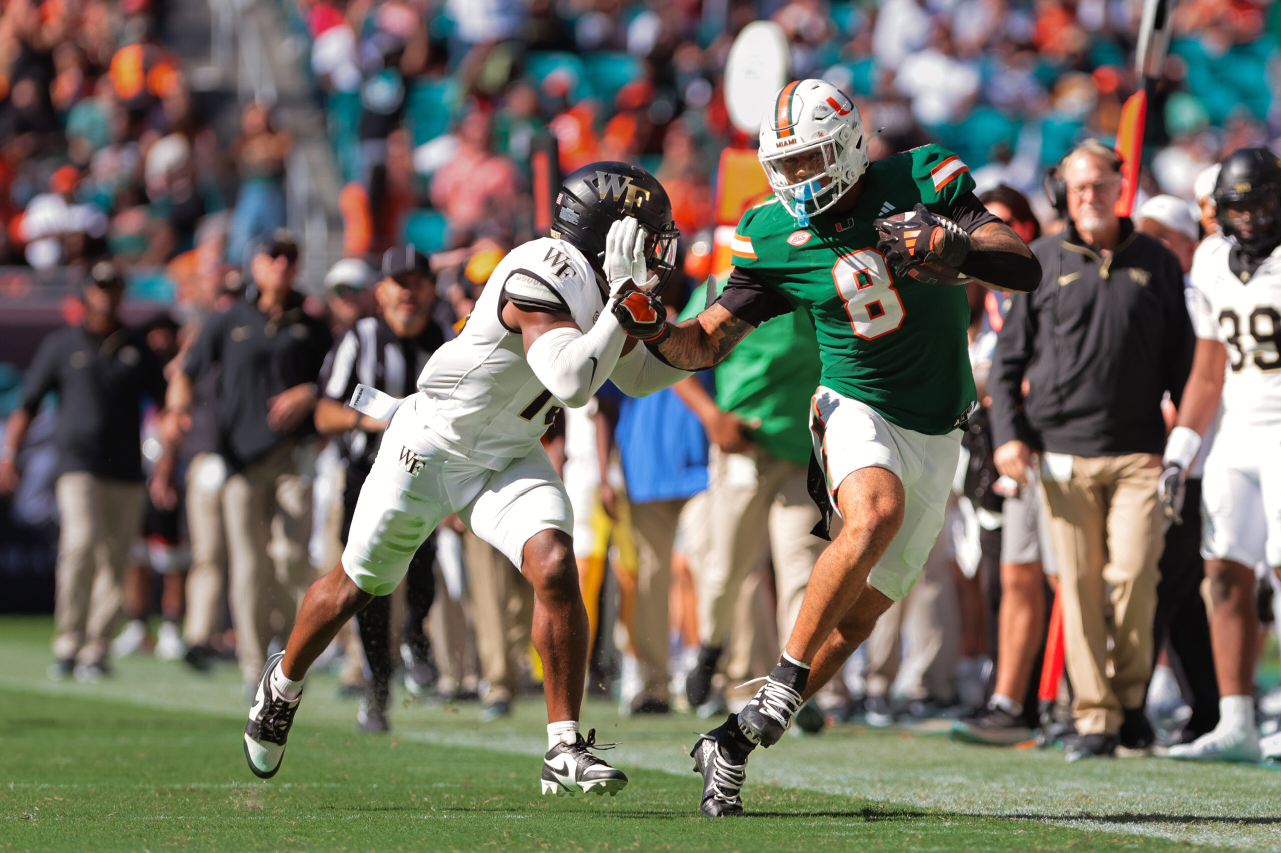 Nov 23, 2024; Miami Gardens, Florida, USA; Miami Hurricanes tight end Elijah Arroyo (8) runs with the football against Wake Forest Demon Deacons defensive back Davaughn Patterson (13) during the second quarter at Hard Rock Stadium.