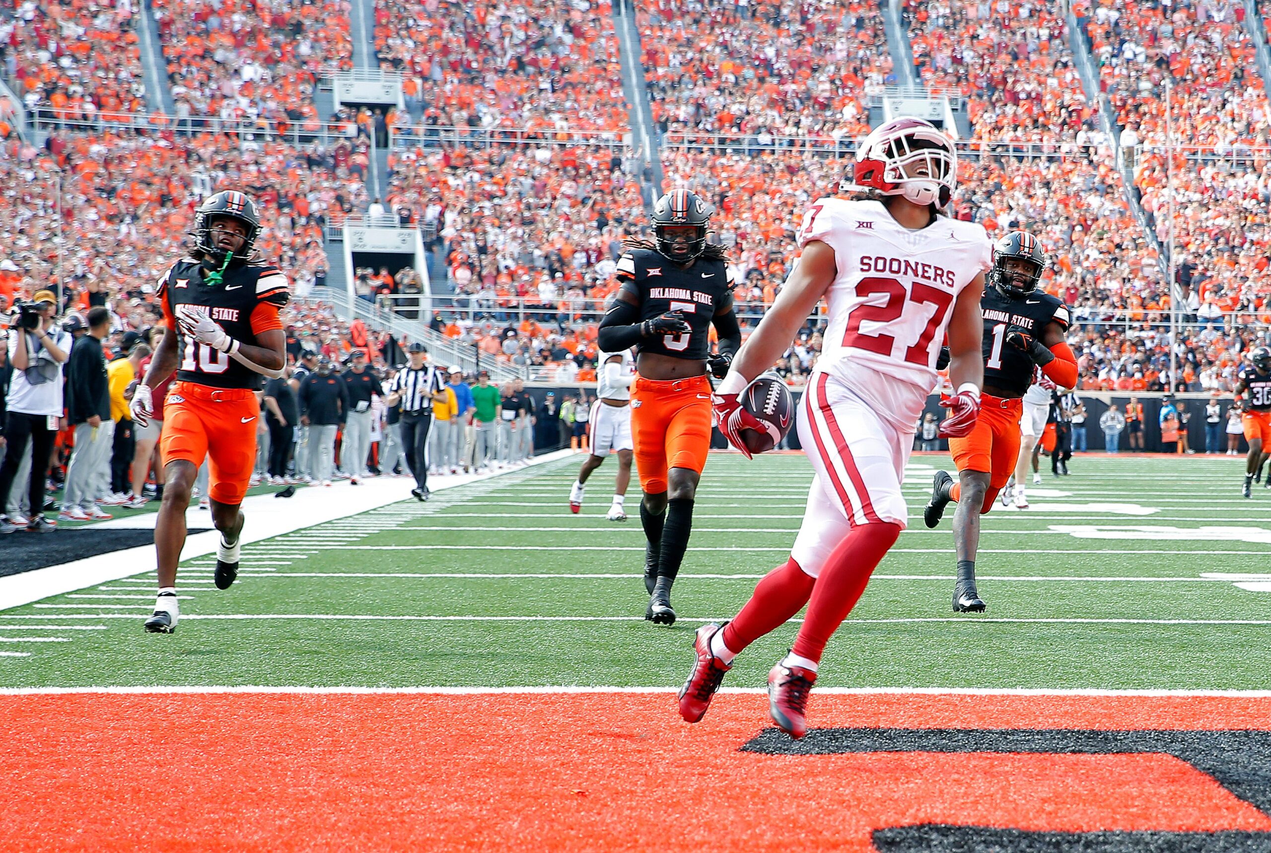 Oklahoma's Gavin Sawchuk (27) scores a touchdown in front of Oklahoma State's Kale Smith (10), Kendal Daniels (5) and Xavier Benson (1)in the first half during a Bedlam college football game between the Oklahoma State University Cowboys (OSU) and the University of Oklahoma Sooners (OU) at Boone Pickens Stadium in Stillwater, Okla., Saturday, Nov. 4, 2023.