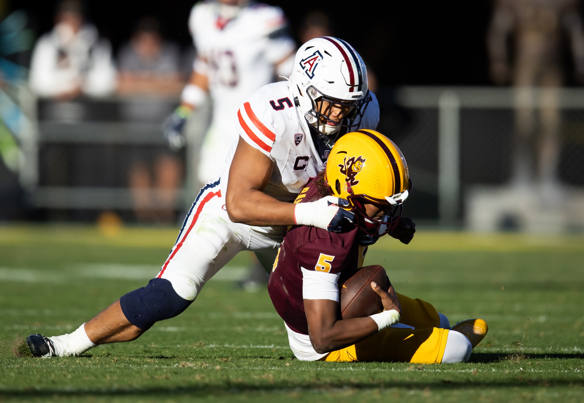 Nov 25, 2023; Tempe, Arizona, USA; Arizona Wildcats linebacker Jacob Manu (top) sacks Arizona State Sun Devils quarterback Jaden Rashada in the second half of the Territorial Cup at Mountain America Stadium.
