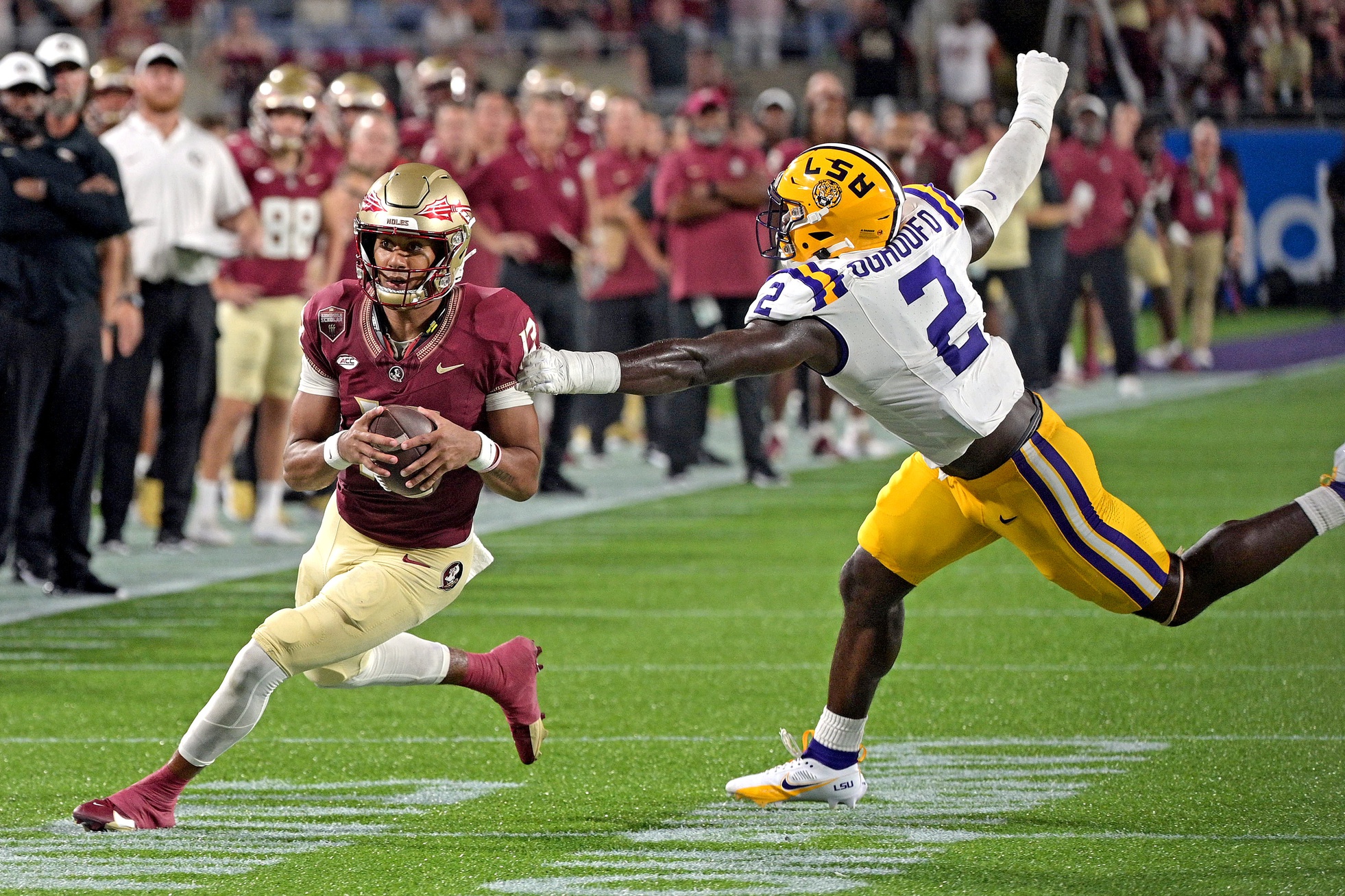 Sep 3, 2023; Orlando, Florida, USA; Florida State Seminoles quarterback Jordan Travis (13) runs away from Louisiana State Tigers linebacker Ovie Oghoufo (2) during the second half at Camping World Stadium.