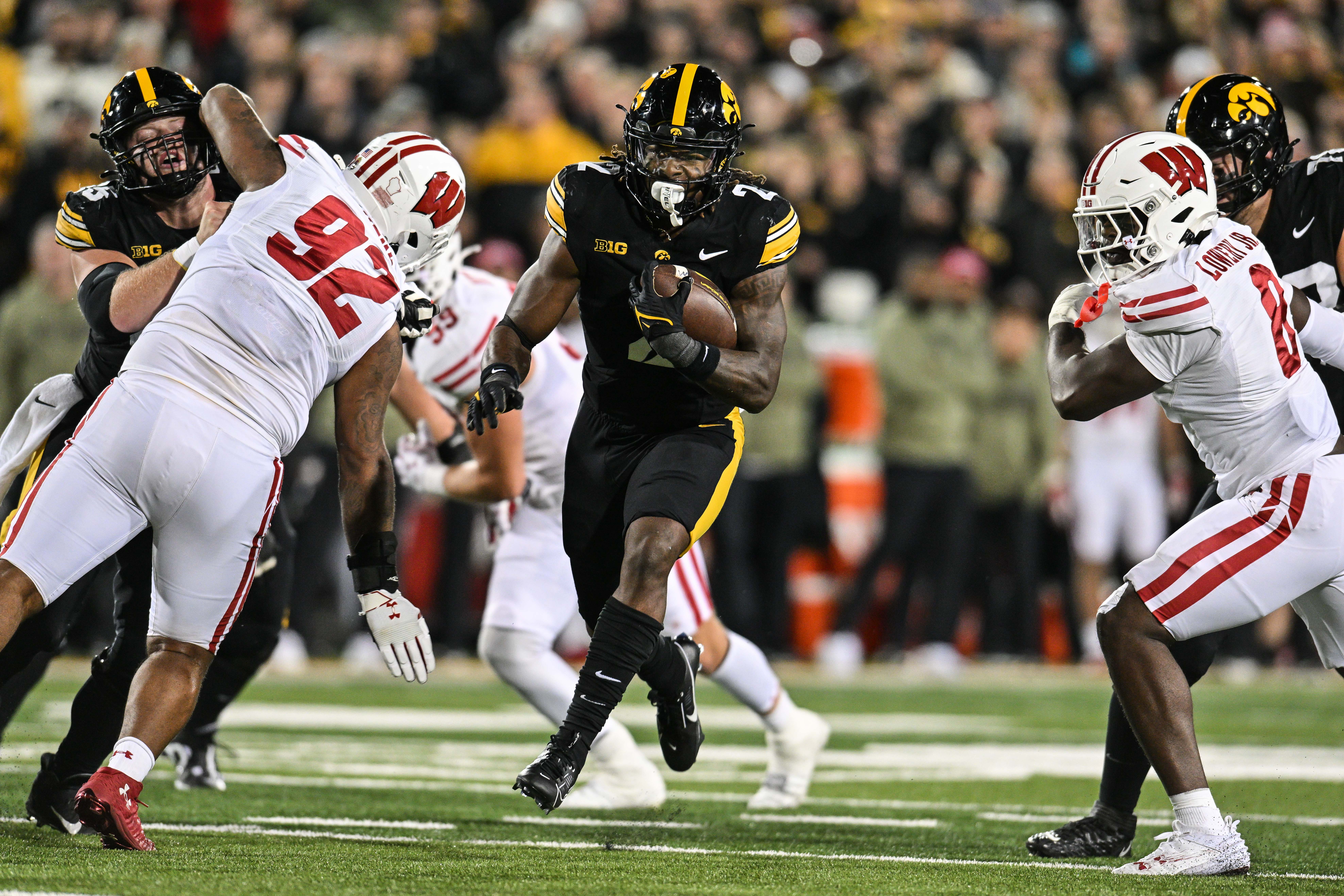 Nov 2, 2024; Iowa City, Iowa, USA; Iowa Hawkeyes running back Kaleb Johnson (2) runs for a 16 yard touchdown as Wisconsin Badgers defensive lineman Curt Neal (92) and linebacker Leon Lowery Jr. (8) attempt to make the tackle during the second quarter at Kinnick Stadium.