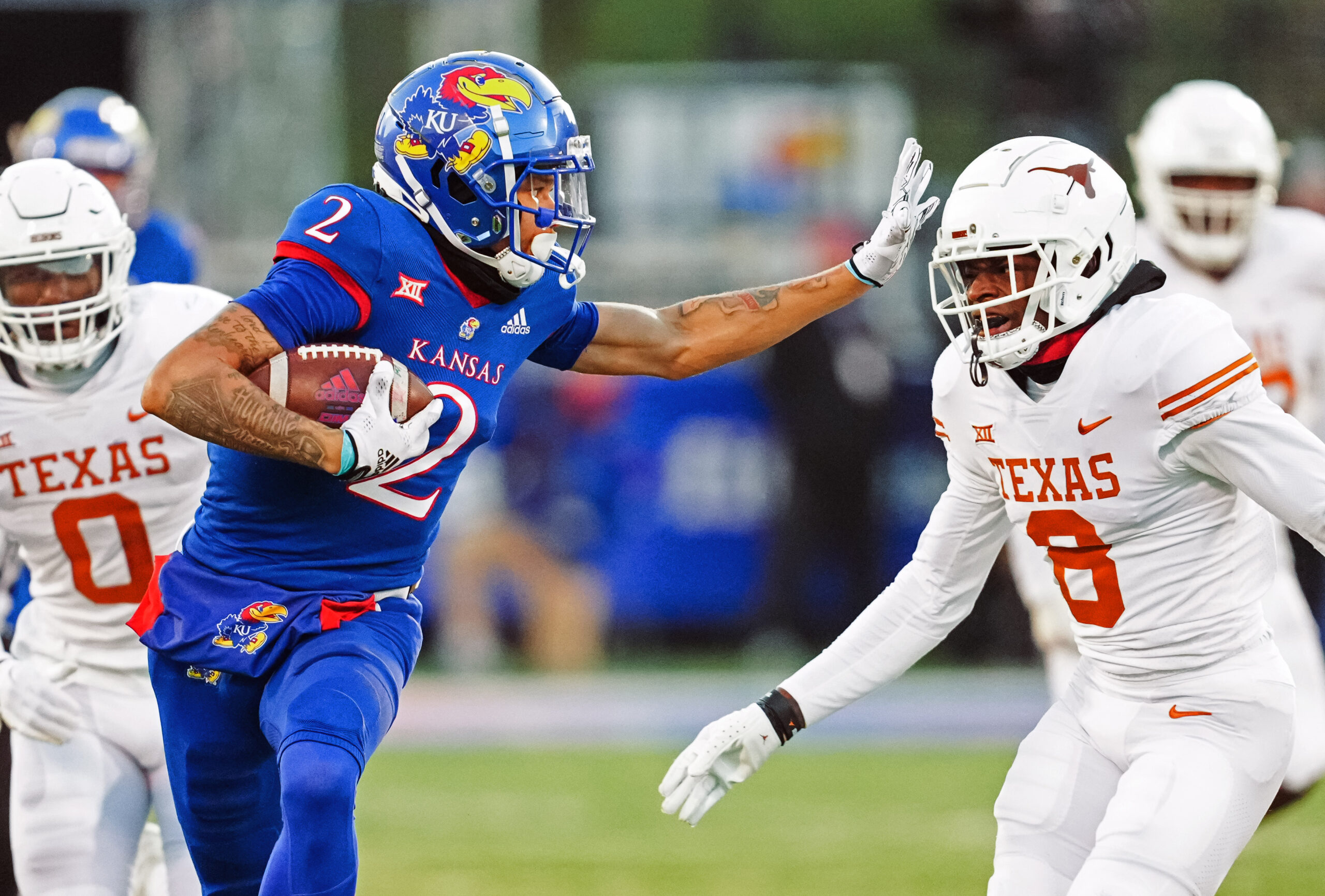 Nov 19, 2022; Lawrence, Kansas, USA; Kansas Jayhawks wide receiver Lawrence Arnold (2) stiff arms Texas Longhorns defensive back Terrance Brooks (8) during the second half at David Booth Kansas Memorial Stadium.