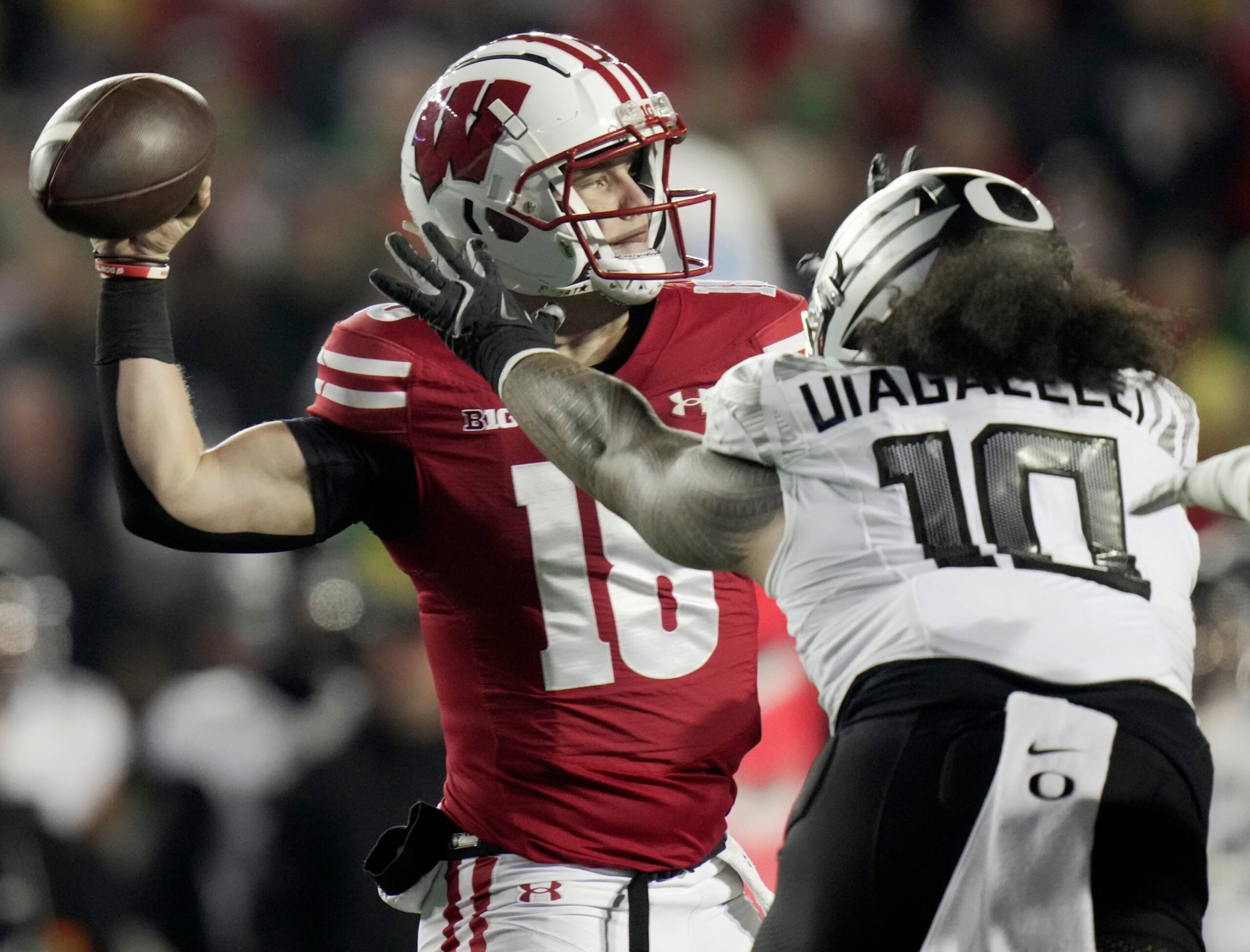 Wisconsin quarterback Braedyn Locke (18) is pressured by Oregon defensive end Matayo Uiagalelei (10) during the first quarter of their game Saturday, November 16, 2024 at Camp Randall Stadium in Madison, Wisconsin.