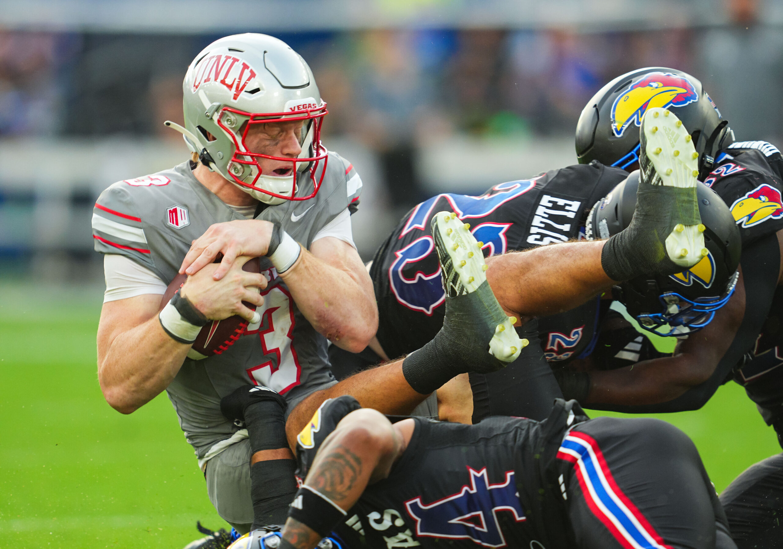 Sep 13, 2024; Kansas City, Kansas, USA; UNLV Rebels quarterback Matthew Sluka (3) is tackled by several Kansas Jayhawks during the first half at Children's Mercy Park.
