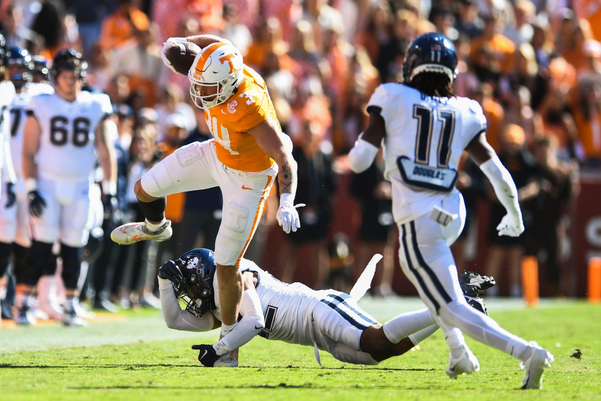Tennessee tight end McCallan Castles (34) trips over a UConn football player during the Tennessee football game against UConn at Neyland Stadium in Knoxville, Tenn., on Saturday, Nov. 4, 2023.