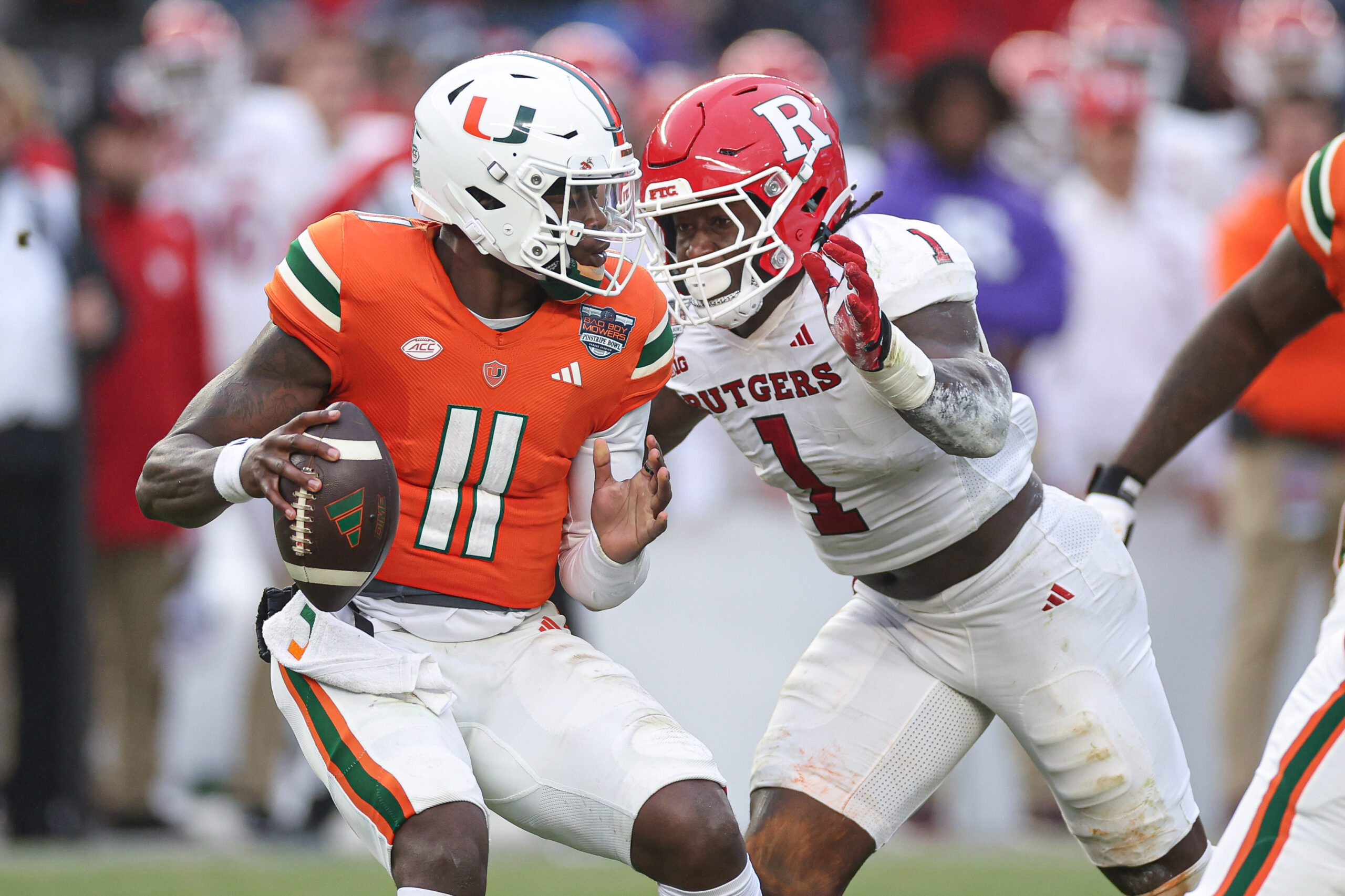 Dec 28, 2023; Bronx, NY, USA; Miami Hurricanes quarterback Jacurri Brown (11) is sacked by Rutgers Scarlet Knights linebacker Mohamed Toure (1) during the first half of the 2023 Pinstripe Bowl at Yankee Stadium.