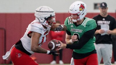 Louisville football quarterback Tyler Shough (9) and running back Peny Boone (13) run drills during spring practice on Saturday