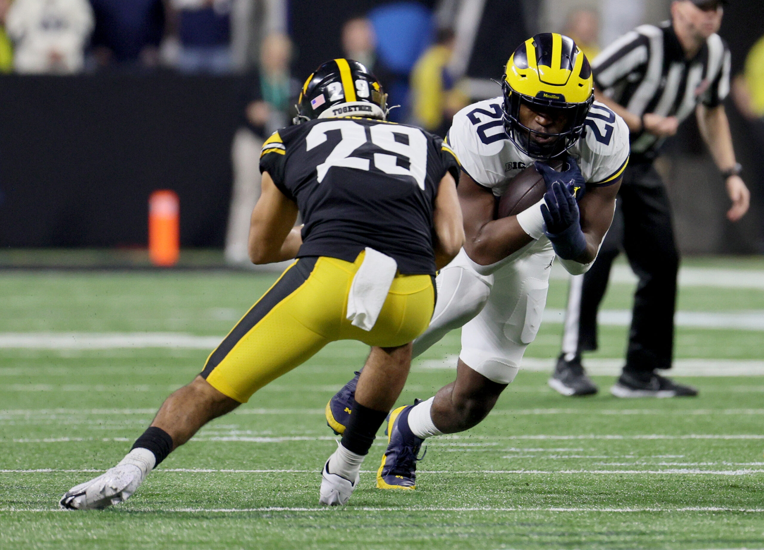 Dec 2, 2023; Indianapolis, IN, USA; Michigan Wolverines running back Kalel Mullings (20) is tackled by Iowa Hawkeyes defensive back Sebastian Castro (29) during the first quarter of the Big Ten Championship game at Lucas Oil Stadium.