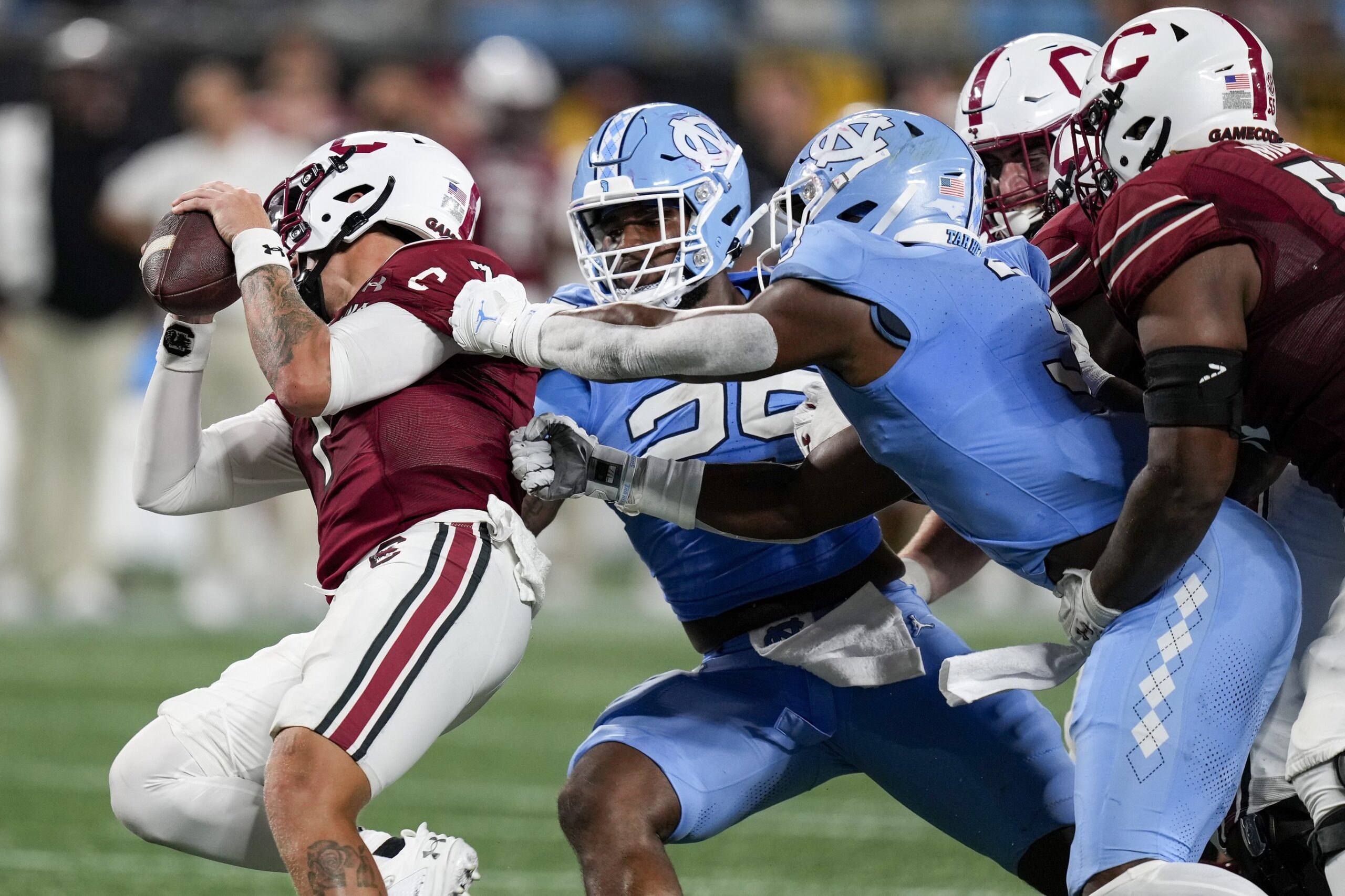 Sep 2, 2023; Charlotte, North Carolina, USA; North Carolina Tar Heels linebacker Kaimon Rucker (25) and linebacker Amari Gainer (3) tackle South Carolina Gamecocks quarterback Spencer Rattler (7) during the second half at Bank of America Stadium.