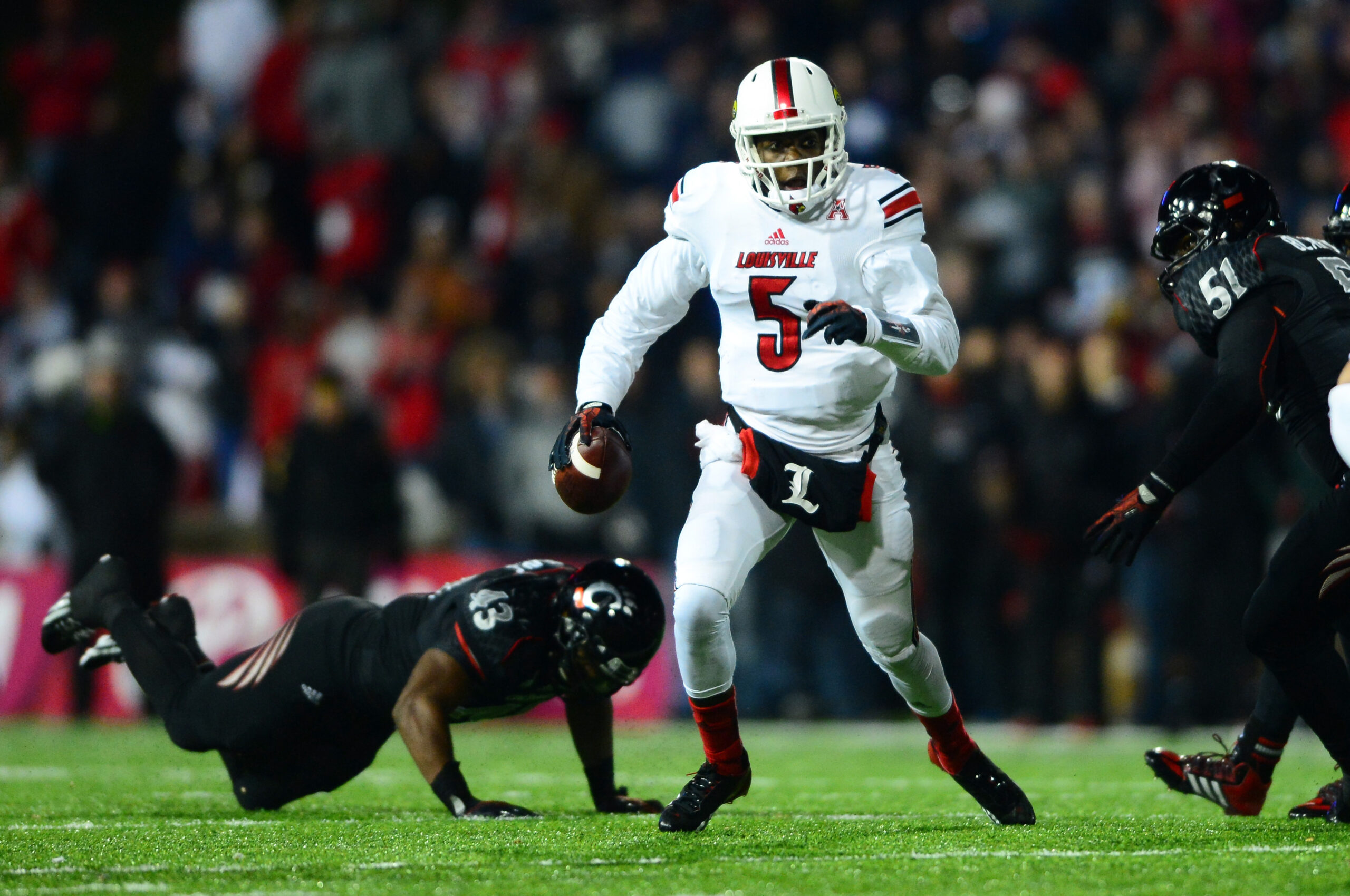 Dec 5, 2013; Cincinnati, OH, USA; Louisville Cardinals quarterback Teddy Bridgewater (5) scrambles out of the pocket and throws a pass for a touchdown during the fourth quarter against the Cincinnati Bearcats at Nippert Stadium.