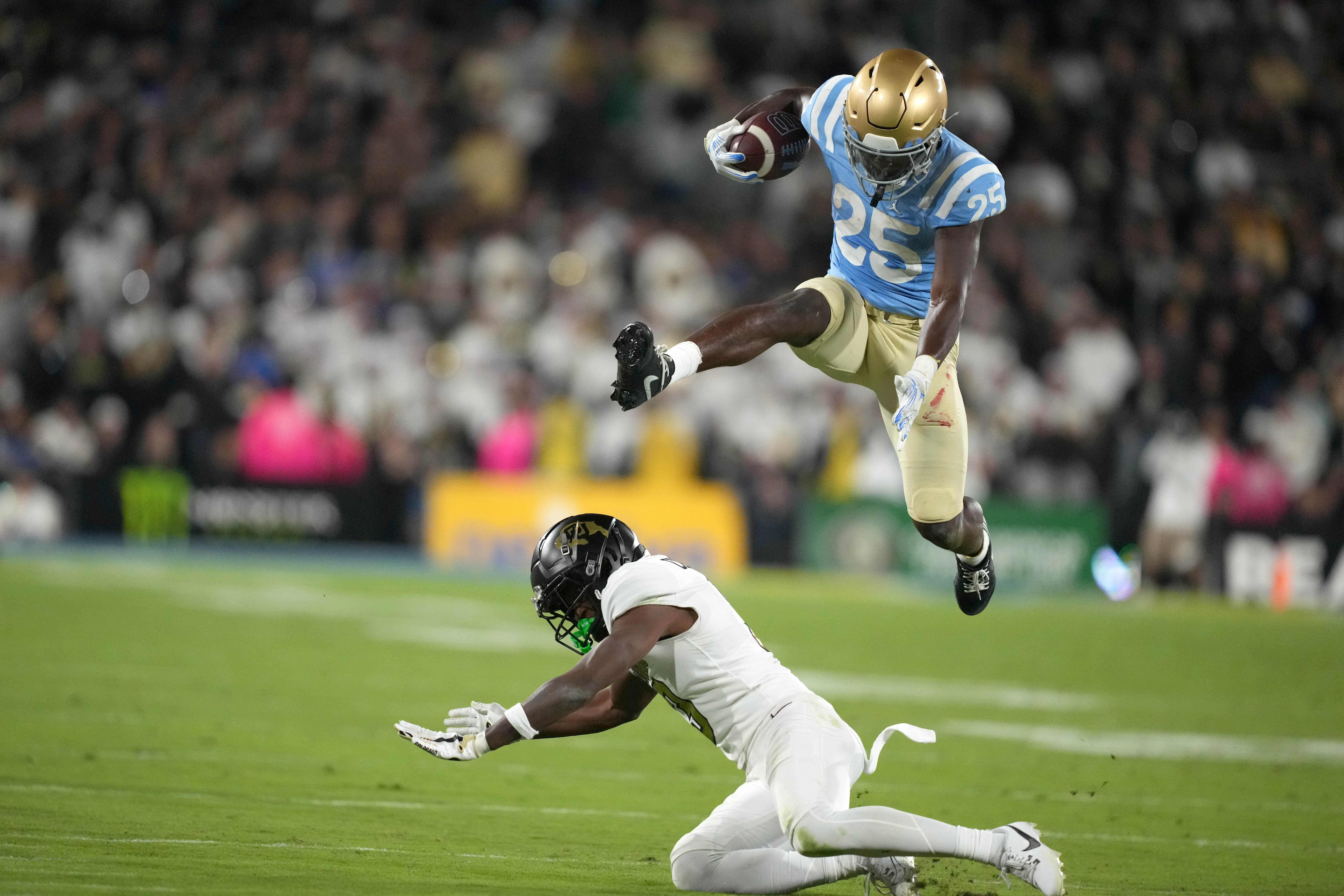 Oct 28, 2023; Pasadena, California, USA; UCLA Bruins running back TJ Harden (25) hurdles Colorado Buffaloes cornerback Omarion Cooper (3) in the second half at Rose Bowl. UCLA defeated Coloradao 28-16.