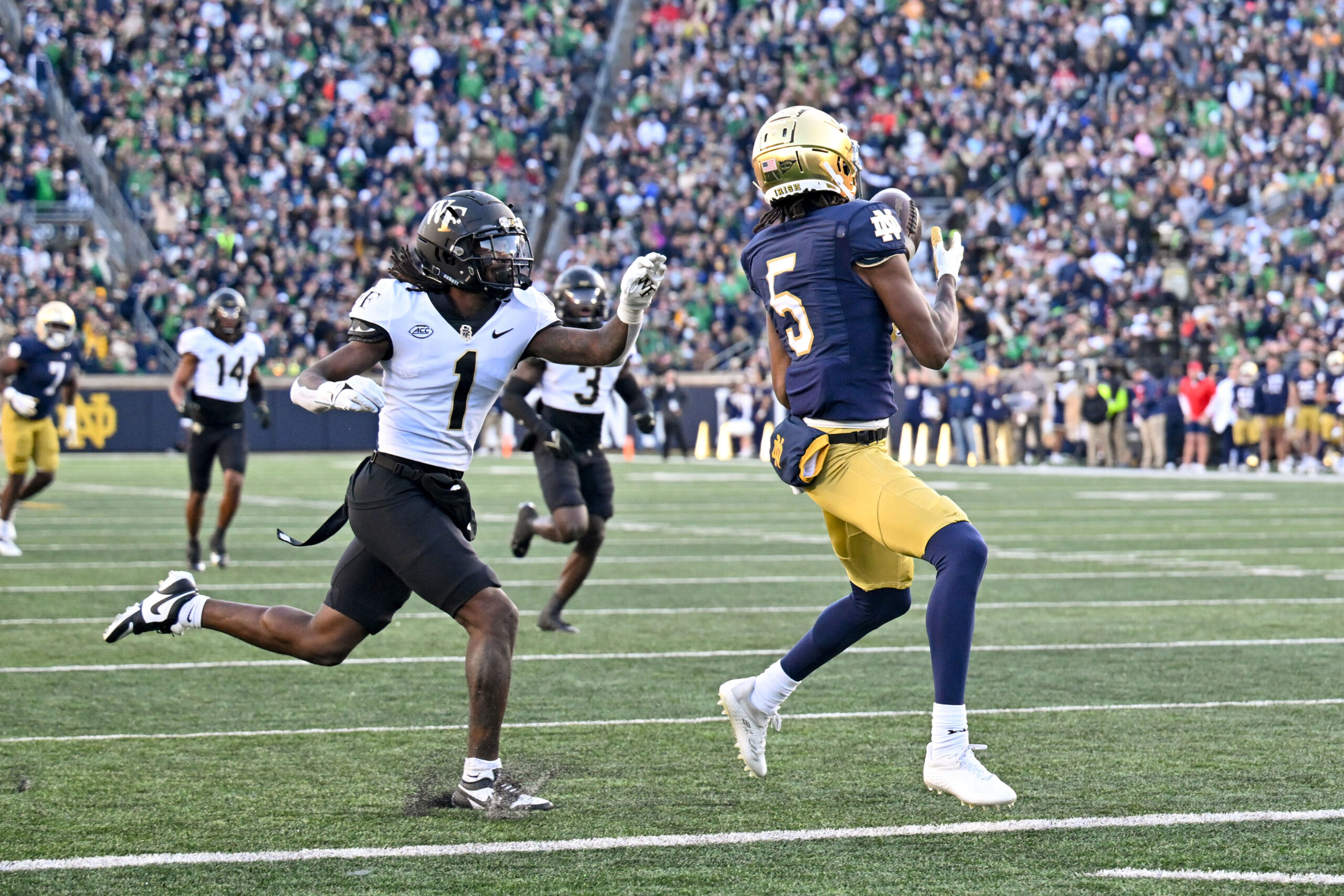 Nov 18, 2023; South Bend, Indiana, USA; Notre Dame Fighting Irish wide receiver Tobias Merriweather (5) catches a pass for a touchdown in front of Wake Forest Demon Deacons cornerback Caelen Carson (1) in the second quarter at Notre Dame Stadium.