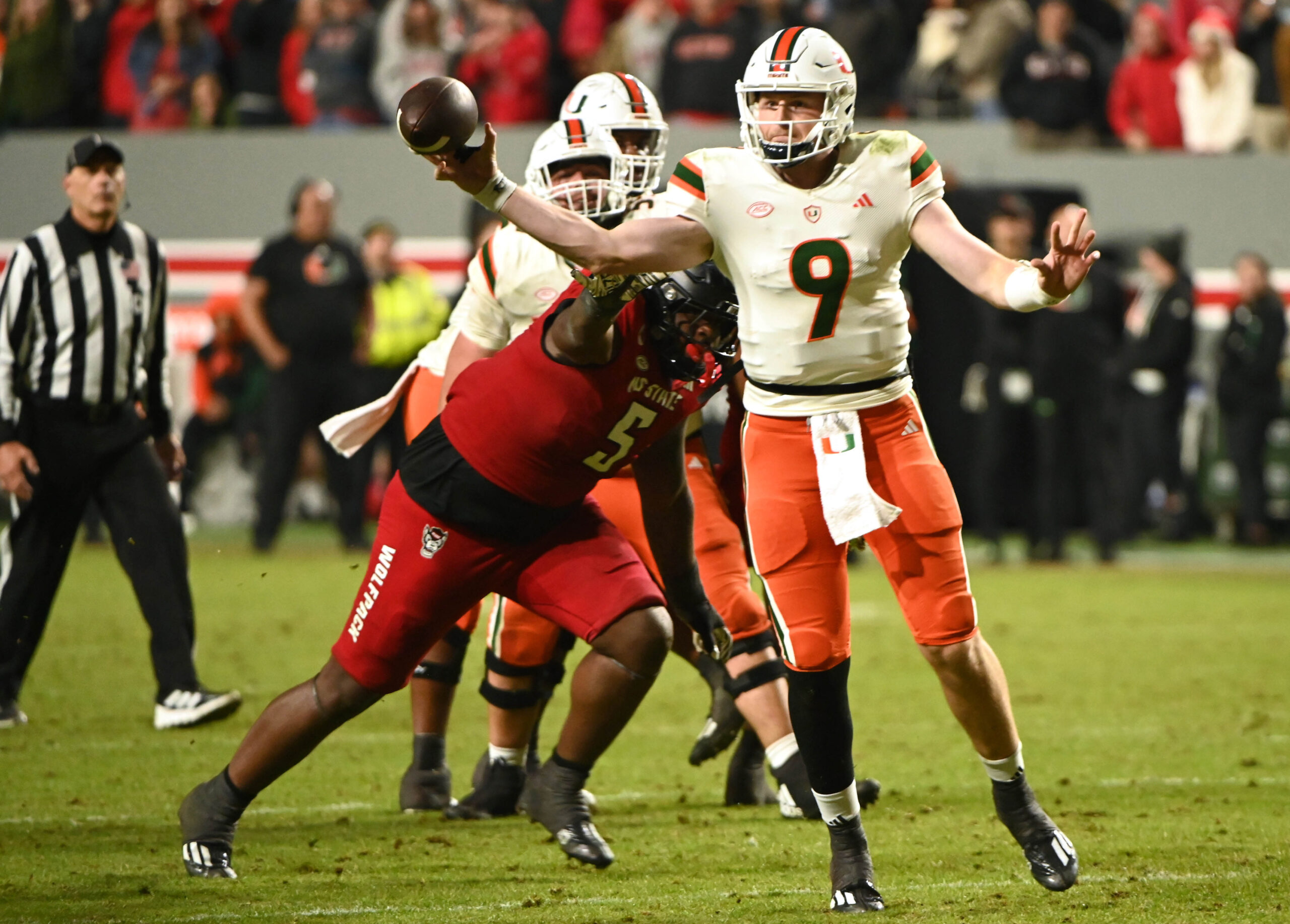 Nov 4, 2023; Raleigh, North Carolina, USA; Miami Hurricanes quarterback Tyler Van Dyke (9) throws a pass as he is pressured by North Carolina State Wolfpack defensive tackle CJ Clark (5) during the second half at Carter-Finley Stadium.