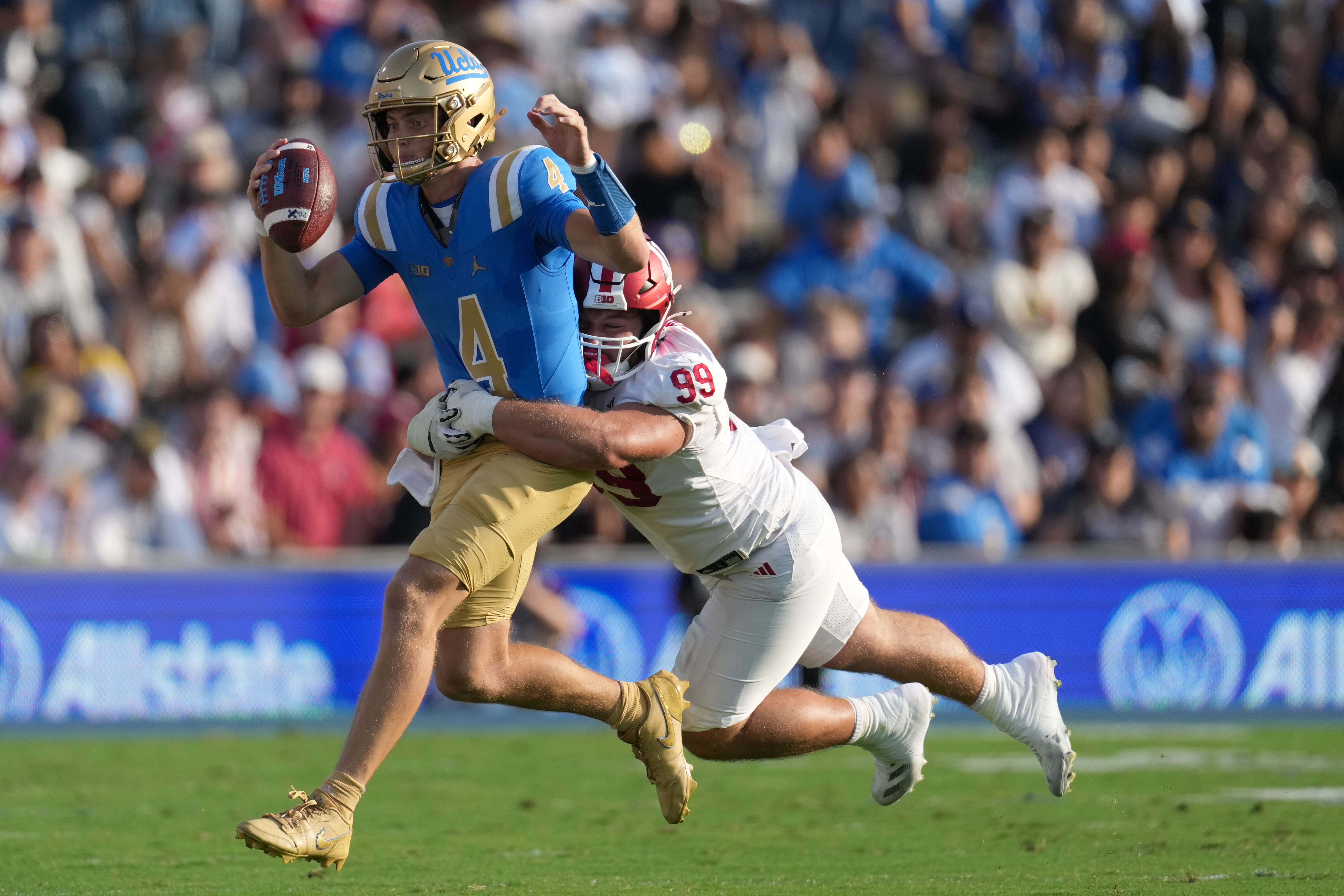 Sep 14, 2024; Pasadena, California, USA; UCLA Bruins quarterback Ethan Garbers (4) is tackled by Indiana Hoosiers defensive lineman James Carpenter (99) in the first half at Rose Bowl.