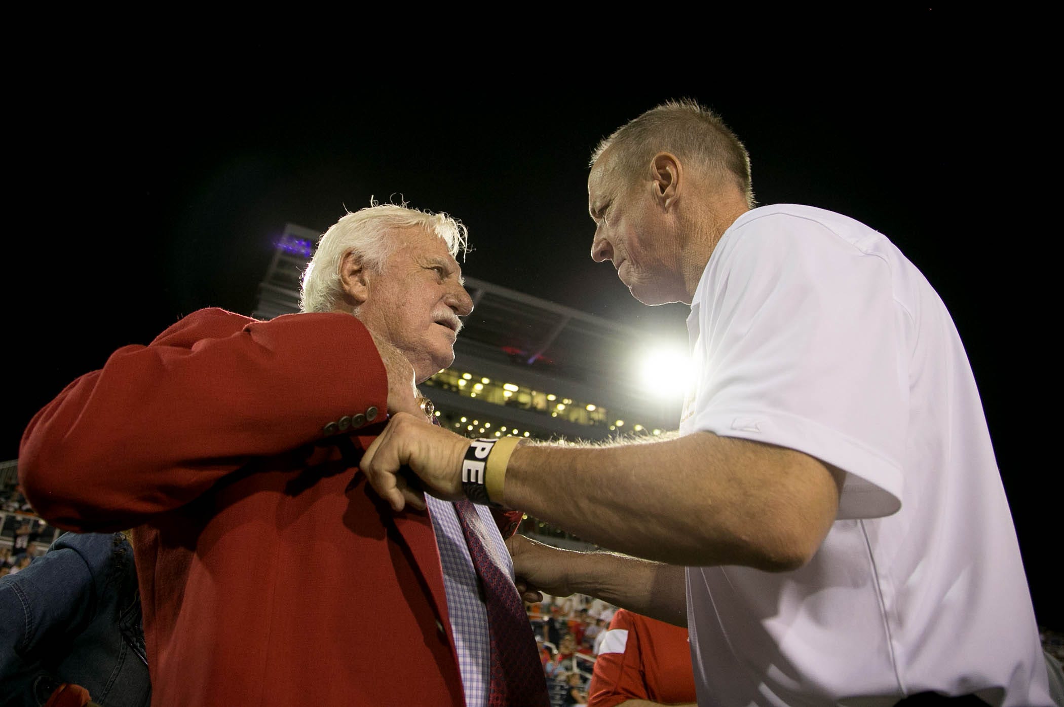 Howard Schnellenberger gets help from Jim Kelly as he puts on his jacket for the coin toss before before the Miami Hurricanes vs Florida Atlantic Owls game at FAU Stadium in Boca Raton, Florida on September 11, 2015.