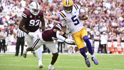 LSU Tigers quarterback Jayden Daniels (5) runs the ball for a touchdown while defended by Mississippi State Bulldogs safety Isaac Smith (20).