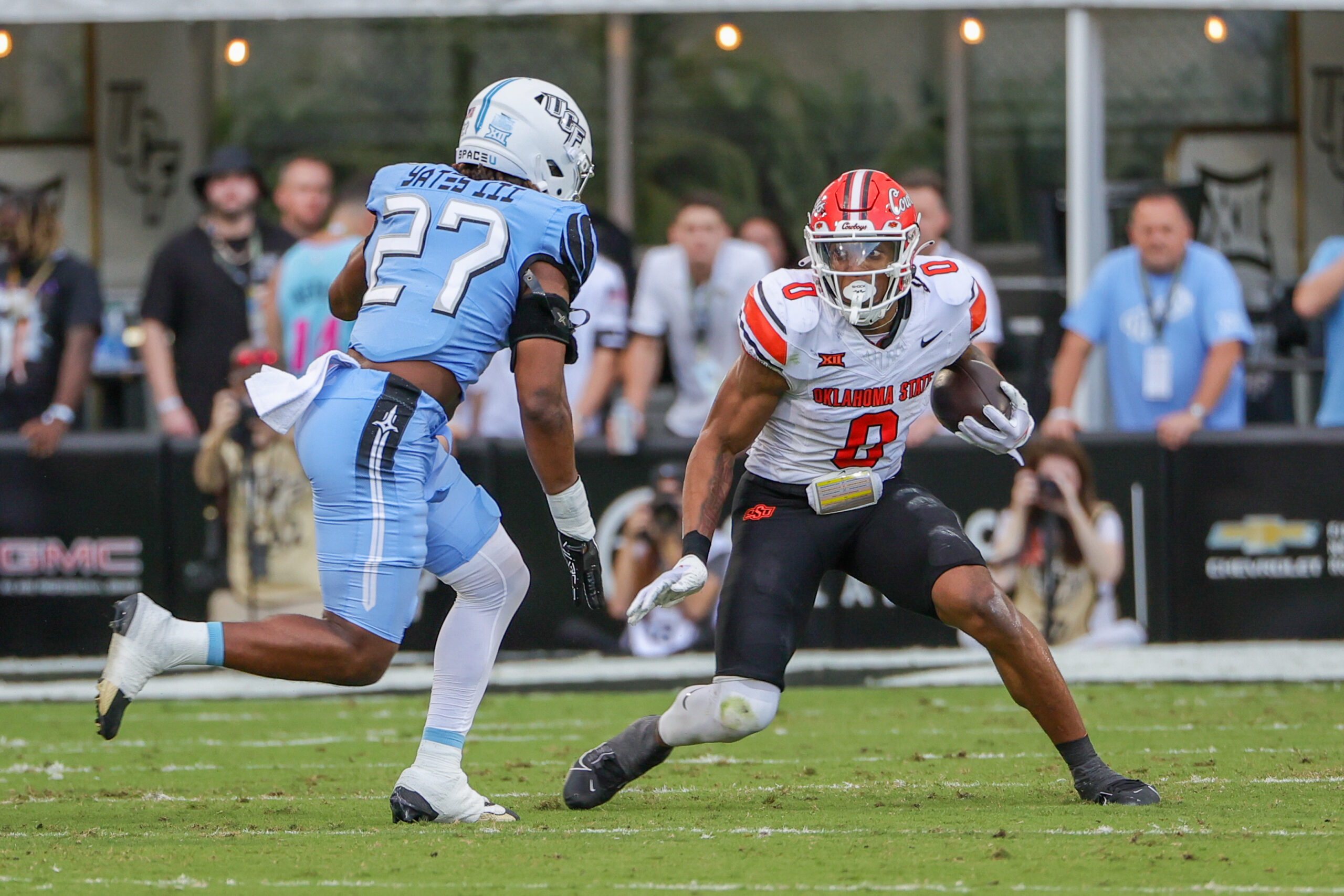 Nov 11, 2023; Orlando, Florida, USA; Oklahoma State Cowboys running back Ollie Gordon II (0) runs the ball in front of UCF Knights linebacker Walter Yates III (27) during the first quarter at FBC Mortgage Stadium