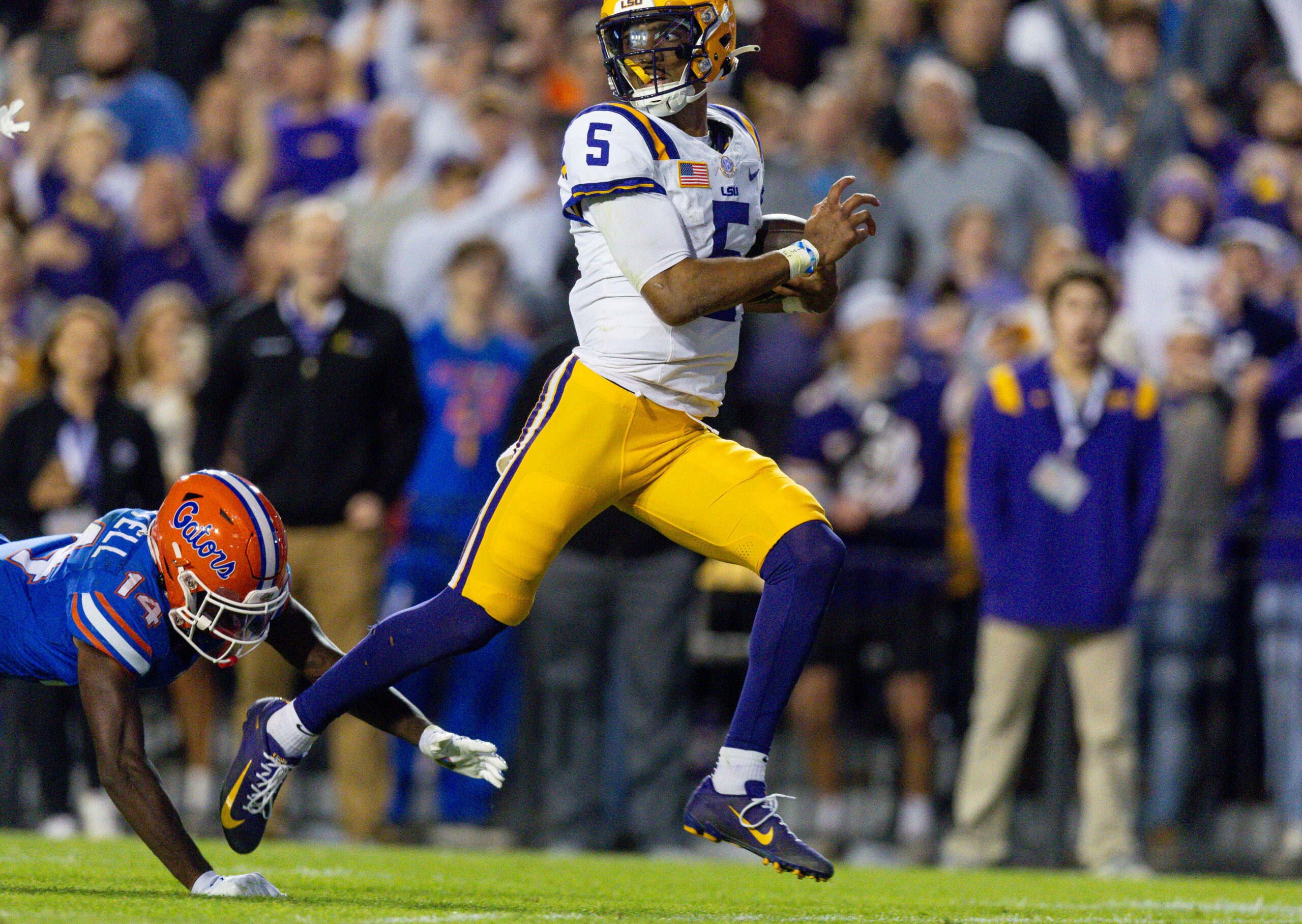Nov 11, 2023; Baton Rouge, Louisiana, USA; LSU Tigers quarterback Jayden Daniels (5) rushes for a touchdown against Florida Gators safety Jordan Castell (14) during the first half at Tiger Stadium.