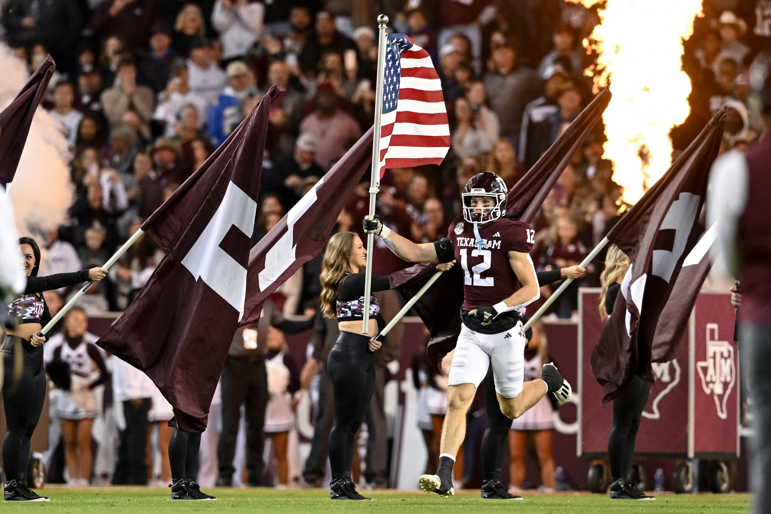 Nov 11, 2023; College Station, Texas, USA; Texas A&M Aggies linebacker Sam Mathews (12) runs out with the American Flag prior to the game against Mississippi State Bulldogs at Kyle Field. 