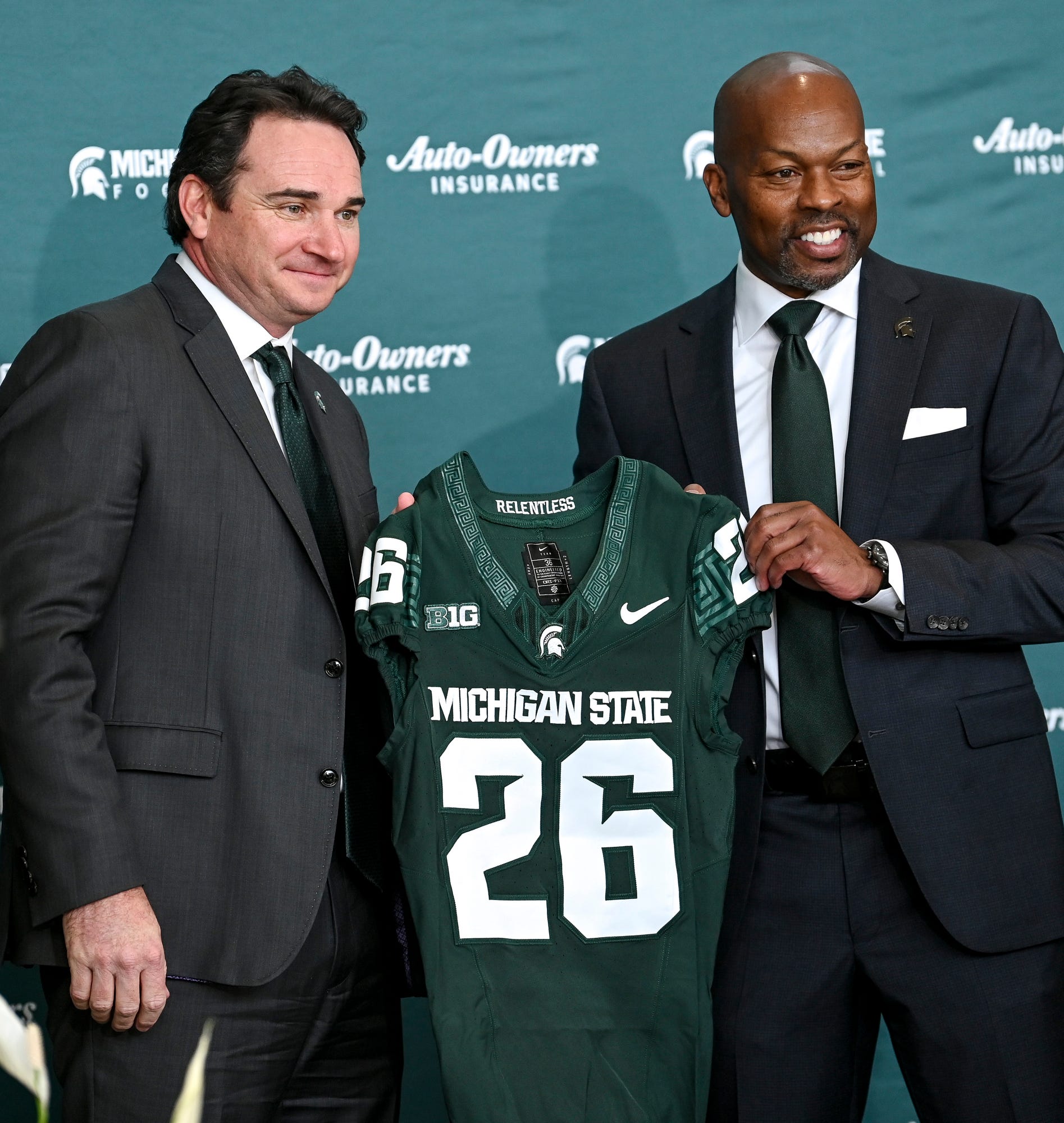 Michigan State football coach Jonathan Smith, left, and athletic director Alan Haller pose with a jersey during an introductory press conference for the new coach on Tuesday, Nov. 28, 2023, at the Breslin Center in East Lansing.