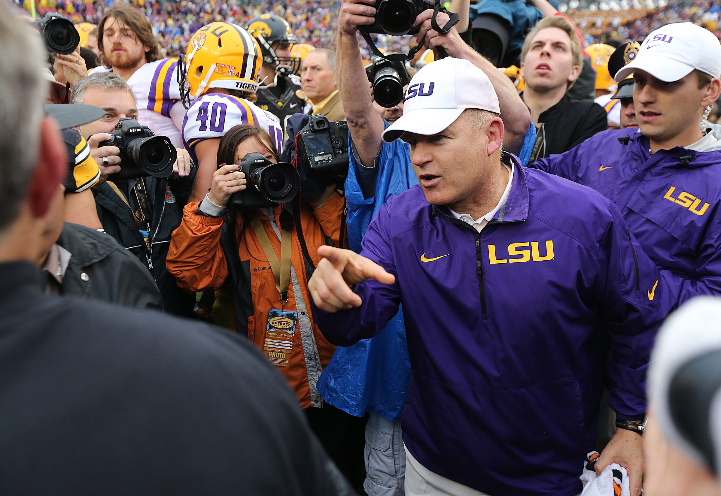 Louisiana State coach Les Miles meets with Iowa coach Kirk Ferentz following Miles and LSU's 21-14 win over the Hawkeyes on Wednesday, Jan. 1, 2014, in Tampa, FL