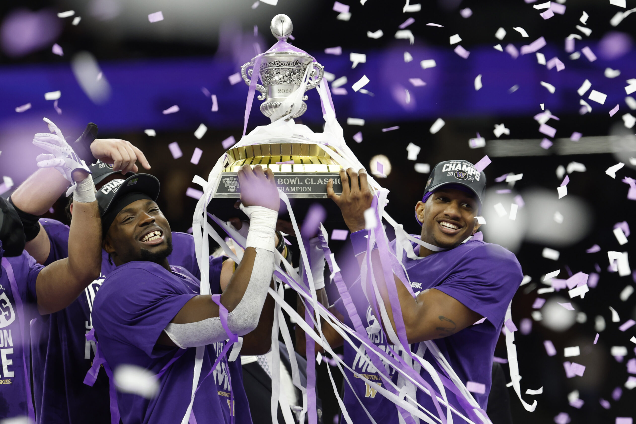 Jan 1, 2024; New Orleans, LA, USA; Washington Huskies quarterback Michael Penix Jr. (R) celebrates with teammates hoisting the Sugar Bowl Trophy after their game against the Texas Longhorns in the 2024 Sugar Bowl college football playoff semifinal game at Caesars Superdome.