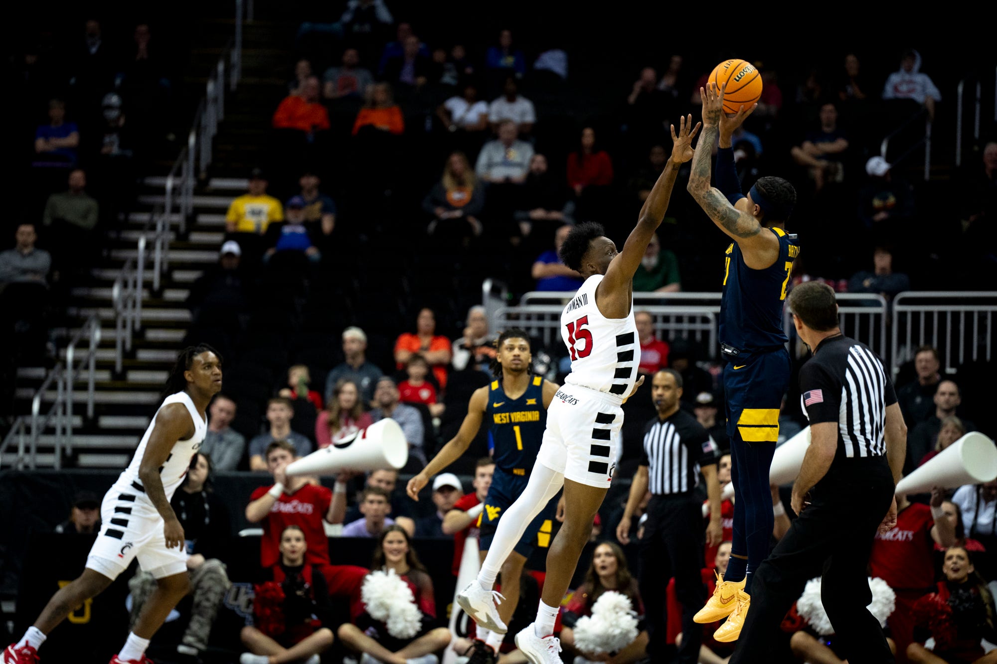 West Virginia Mountaineers guard RaeQuan Battle (21) hits a 3-point basket as Cincinnati Bearcats forward John Newman III (15) defends in the first half of the Big 12 Conference tournament between Cincinnati Bearcats and West Virginia Mountaineers at T-Mobile Center in Kansas City, Mo., on Tuesday, March 12, 2024.