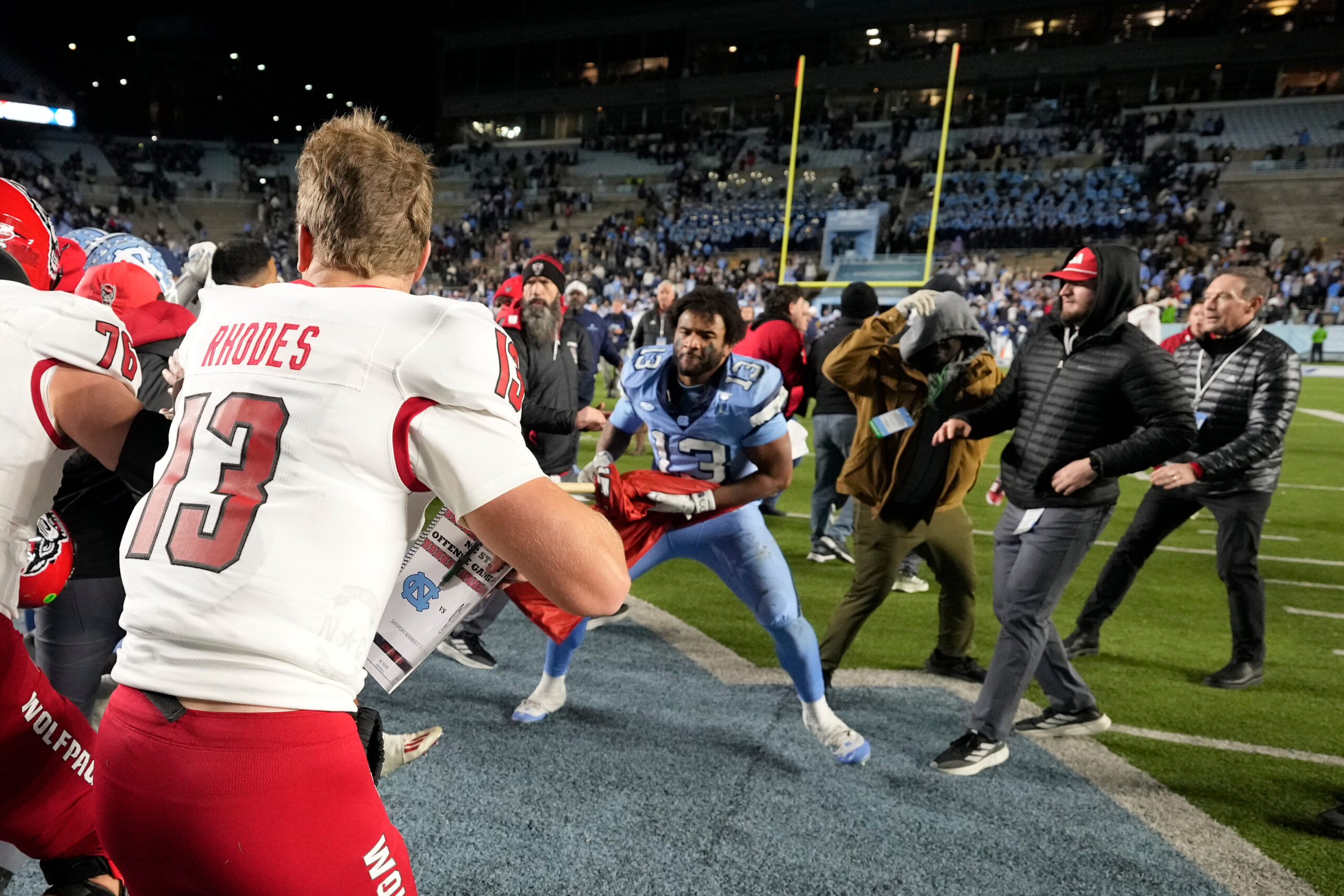 Nov 30, 2024; Chapel Hill, North Carolina, USA; North Carolina Tar Heels players and North Carolina State Wolfpack players fight as State tries to put a Wolfpack flag at midfield after the game at Kenan Memorial Stadium. Mandatory Credit: Bob Donnan-Imagn Images