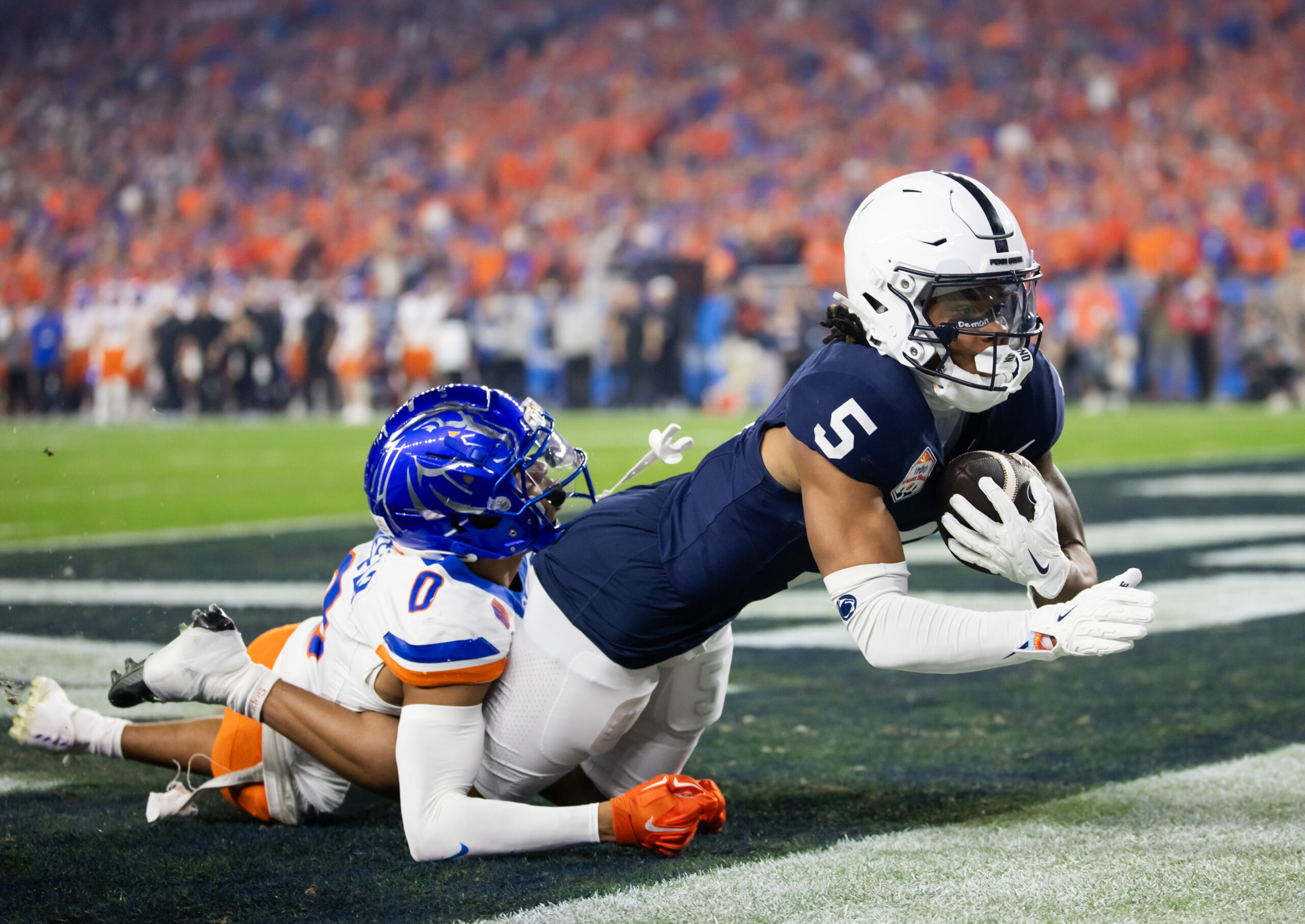 Dec 31, 2024; Glendale, AZ, USA; Penn State Nittany Lions wide receiver Omari Evans (5) makes a touchdown catch over Boise State Broncos safety Ty Benefield (0) during the first half in the Fiesta Bowl at State Farm Stadium.