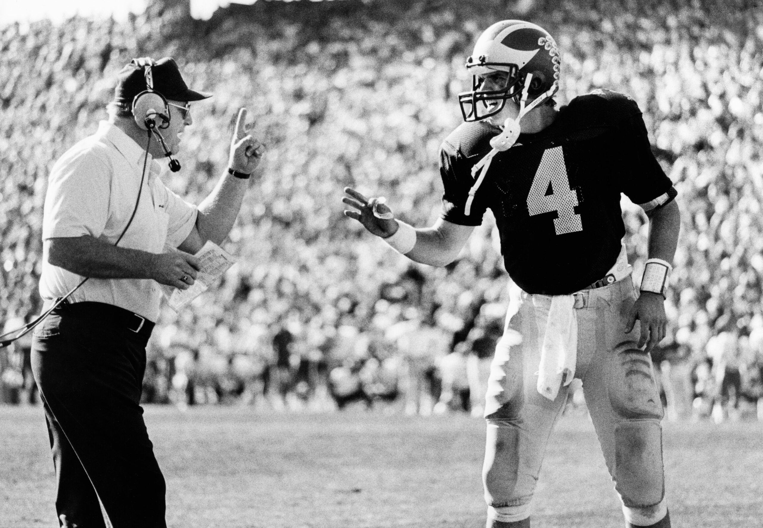 Jan 1, 1986; Tempe, AZ, USA; FILE PHOTO; Michigan Wolverines head coach Bo Schembechler (left) confers with quarterback Jim Harbaugh (4) during the 1986 Sunkist Fiesta Bowl against the Nebraska Cornhuskers at Sun Devil Stadium. The Wolverines defeated the Cornhuskers 27-23.