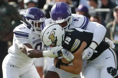 Northwestern Wildcats defensive back Coco Azema (0) and Northwestern Wildcats defensive lineman Anto Saka (4) tackle Purdue Boilermakers quarterback Ryan Browne (15) Saturday, Nov. 2, 2024, during the NCAA football game at Ross-Ade Stadium in West Lafayette, Ind.