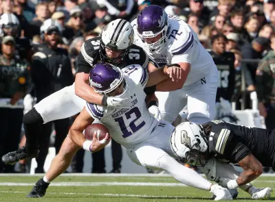 Purdue Boilermakers defensive back Dillon Thieneman (31) and Purdue Boilermakers defensive back Antonio Stevens (11) tackle Northwestern Wildcats quarterback Jack Lausch (12) Saturday, Nov. 2, 2024, during the NCAA football game at Ross-Ade Stadium in West Lafayette, Ind.