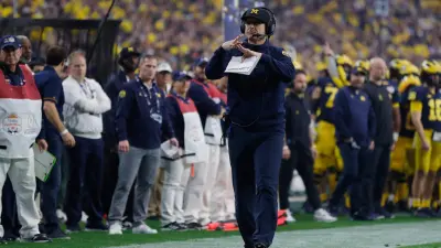 Michigan head coach Jim Harbaugh signals for a timeout in the first quarter against TCU during the Fiesta Bowl on Saturday