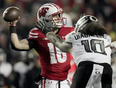 Wisconsin quarterback Braedyn Locke (18) is pressured by Oregon defensive end Matayo Uiagalelei (10) during the first quarter of their game Saturday, November 16, 2024 at Camp Randall Stadium in Madison, Wisconsin.