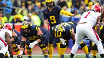 Michigan quarterback J.J. McCarthy talks to teammates before taking a snap from center Drake Nugent against Indiana during the first half at Michigan Stadium in Ann Arbor on Saturday