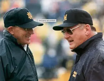 Michigan head coach Bo Schembechler engages with Notre Dame head coach Lou Holtz prior to their 1989 clash.